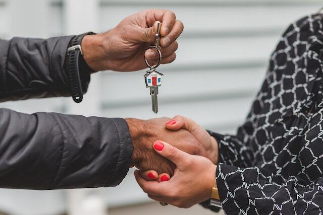people shaking hands and holding a house key